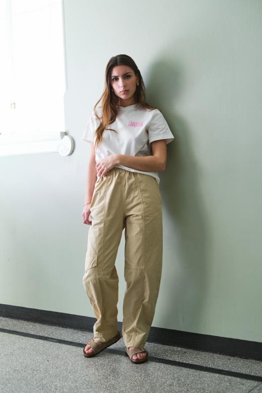 GANNI Washed Cotton Canvas Elasticated Curve Pants Pale Khaki er et par lette bukser som enkelt kan styles både opp og ned. Bruk denne GANNI buksen sammen med en t-skjorte og sandaler, eller style den sammen med et par høye hæler og en bluse.